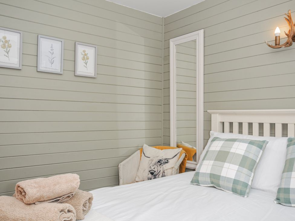 A bedroom with a bed and towels at Cornish Woodland Retreat near St Tudy