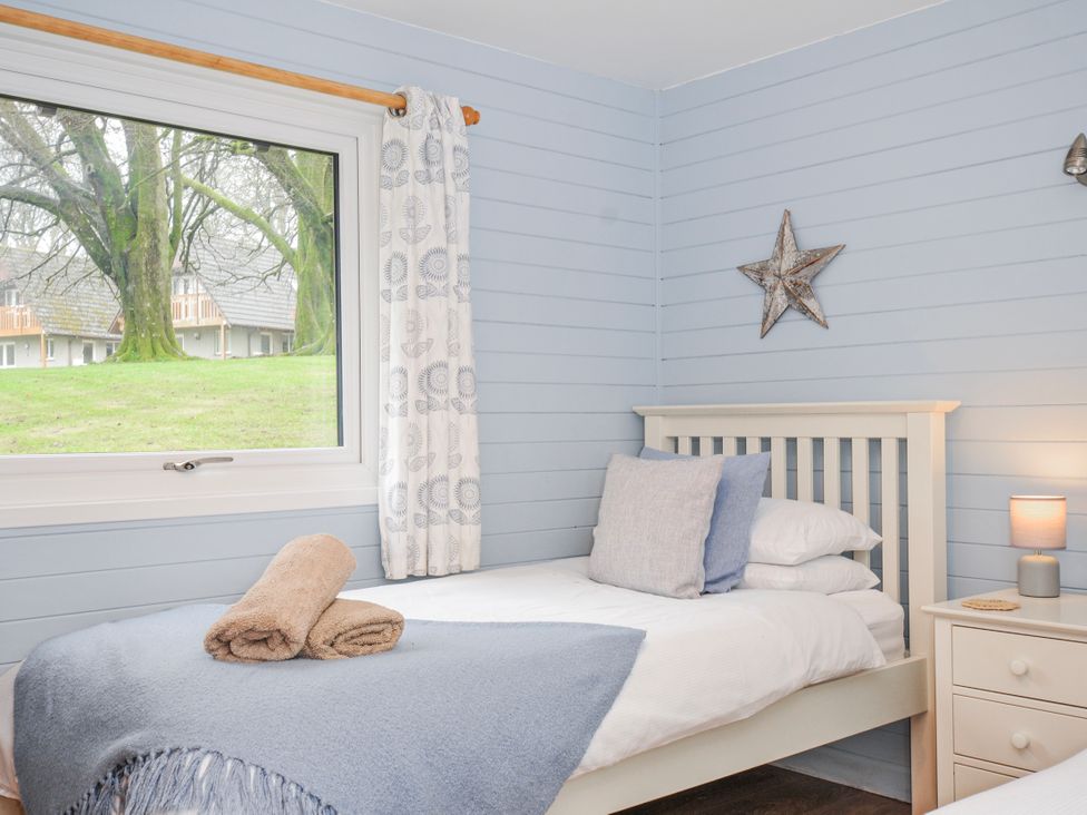 A bedroom with a bed and window at Cornish Woodland Retreat Near St Tudy