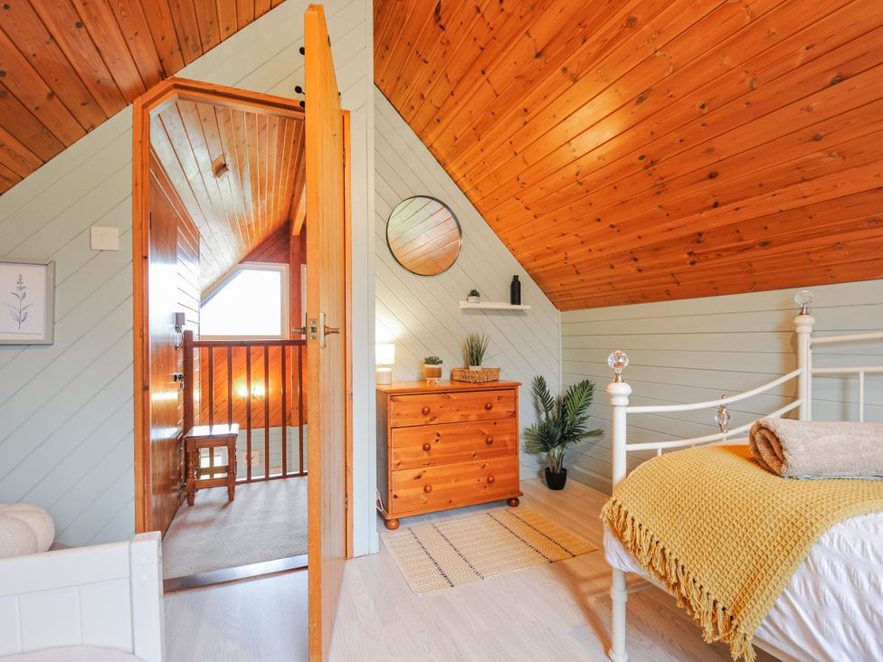 A bedroom with a bed, chest of drawers, and mirror at Cornish Woodland Retreat Near St Tudy