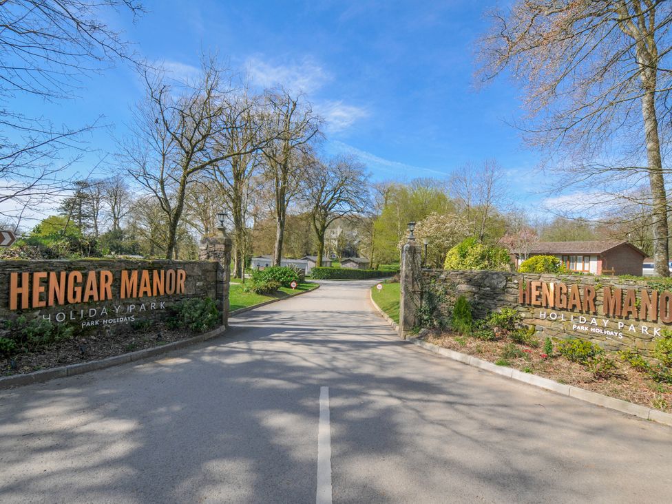 Entrance sign of Hengar Manor Holiday Park with trees and pathway near St Tudy