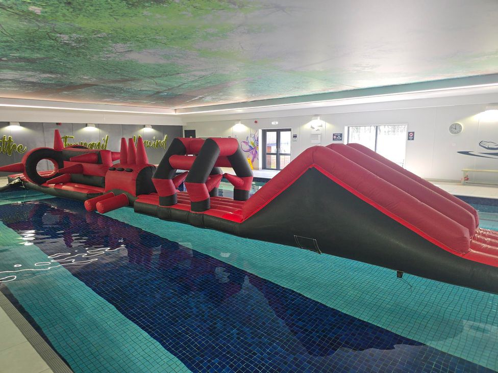 An inflatable obstacle course in an indoor pool at Cornish Woodland Retreat Near St Tudy