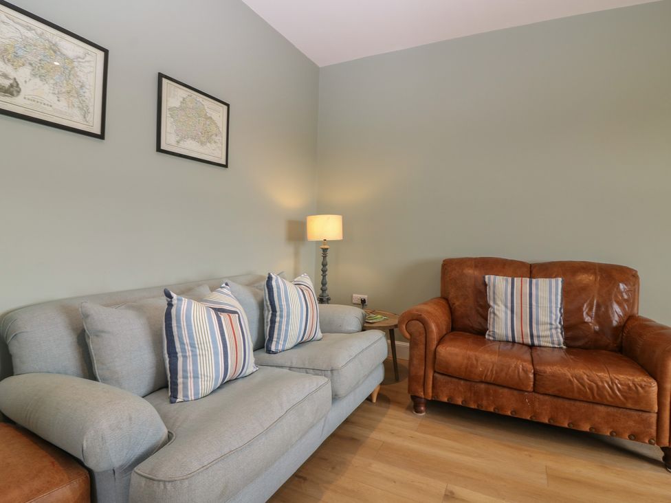 A living room with a grey sofa and brown leather armchair at No 6 - 2 bed Haddington