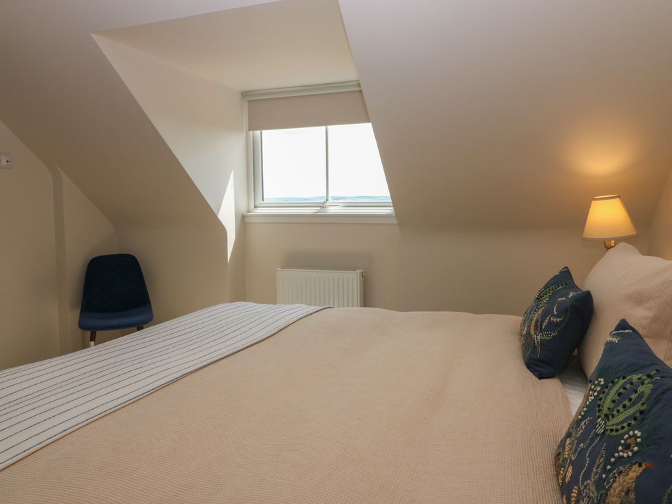 A bedroom with a bed, pillows, chair, window, and radiator at No 6 - 2 bed Haddington