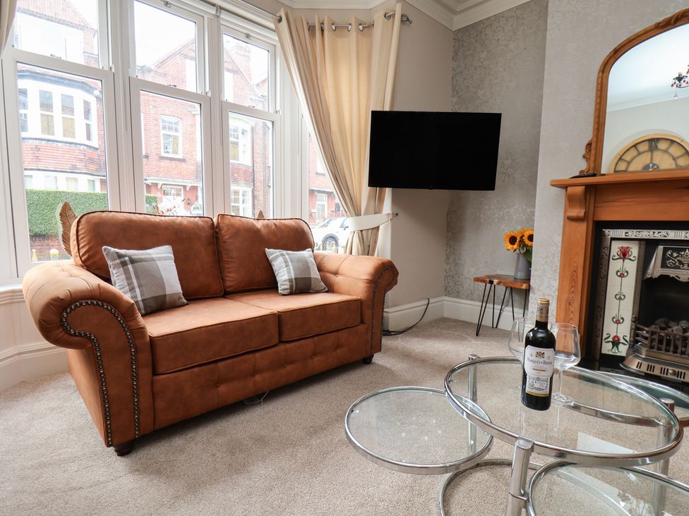 A living room with a sofa, television, and flowers at 11 Rutland Street in Filey