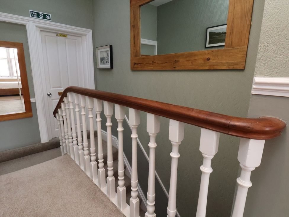 A staircase with a wooden railing in a hallway at 11 Rutland Street in Filey