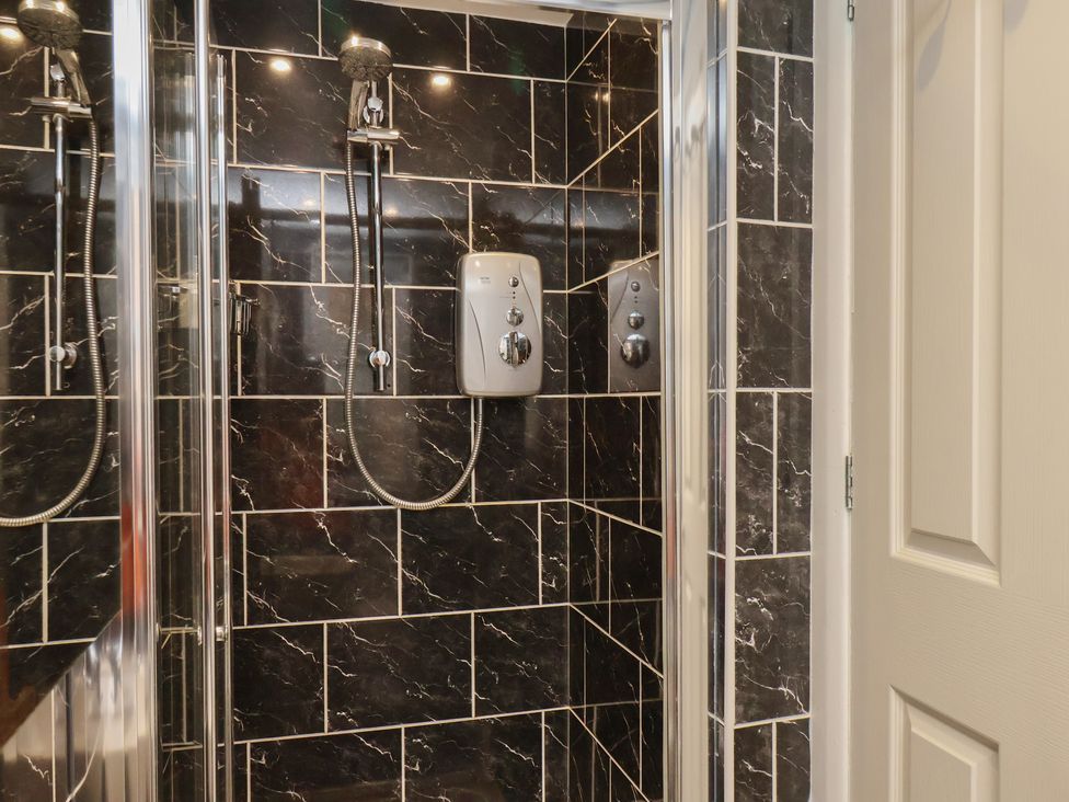 A bathroom with a shower and grey tiles at 11 Rutland Street in Filey