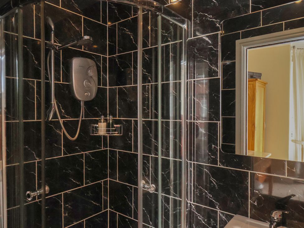 A shower with black tiles and a soap dispenser at 11 Rutland Street, Filey