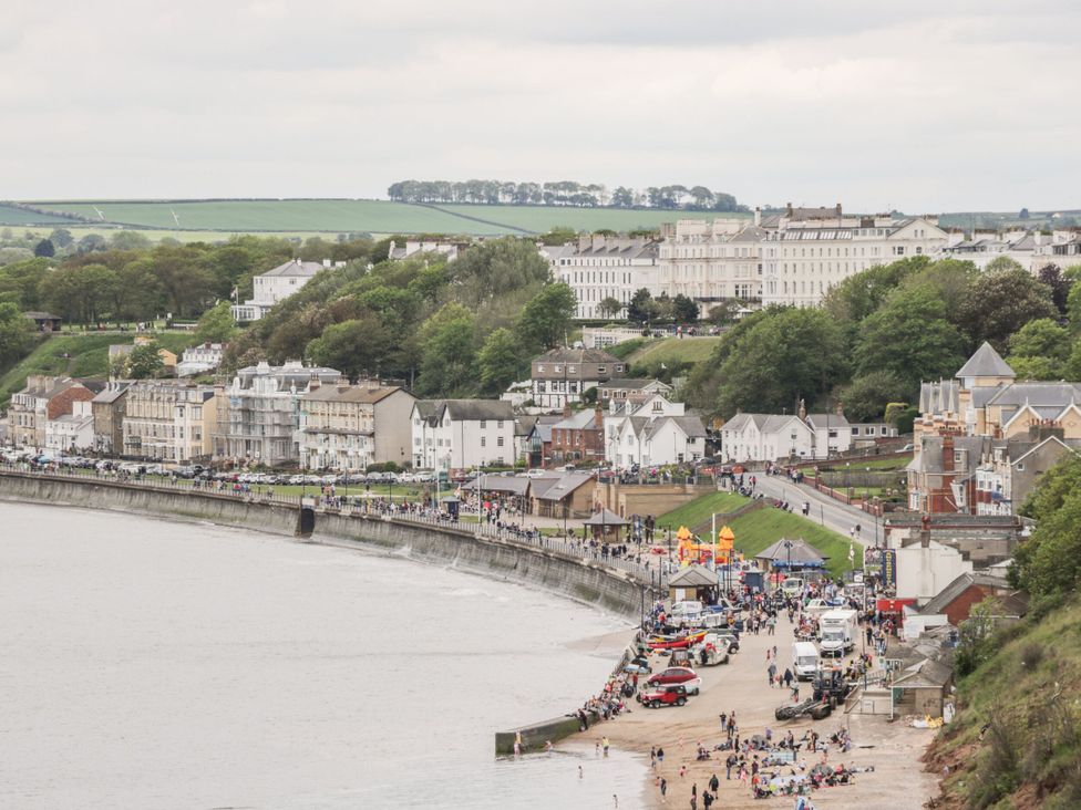 A view of a beach with people and buildings at All Seasons in Filey
