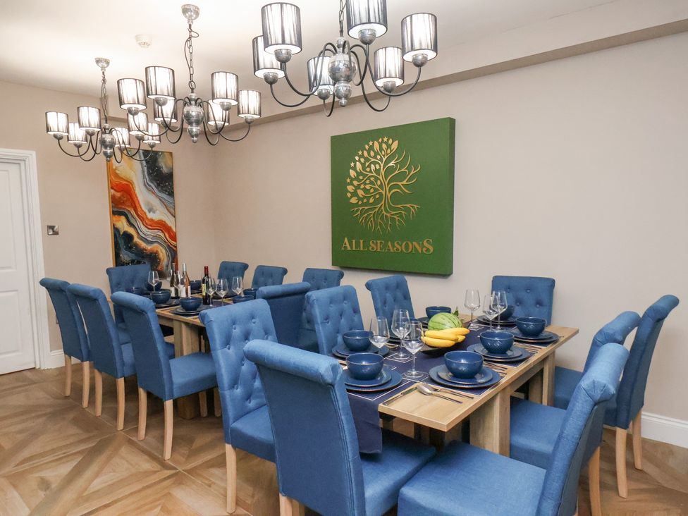 A dining room with a large table and blue chairs at All Seasons in Filey