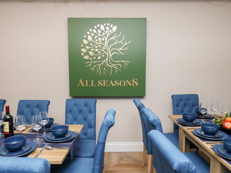 A dining room with blue chairs and table settings at All Seasons in Filey
