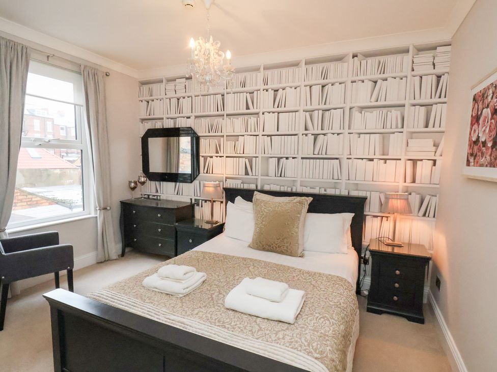 A bedroom with a bed and mirror at All Seasons in Filey