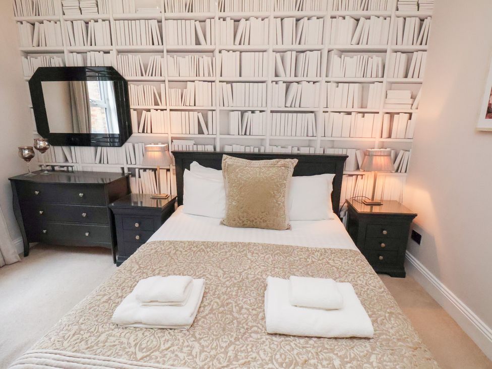 A bedroom with a bed and a wall designed to look like a bookshelf at All Seasons in Filey