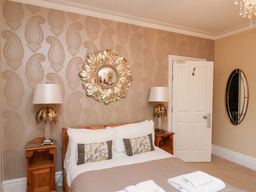A bedroom with a bed and mirrors at All Seasons in Filey