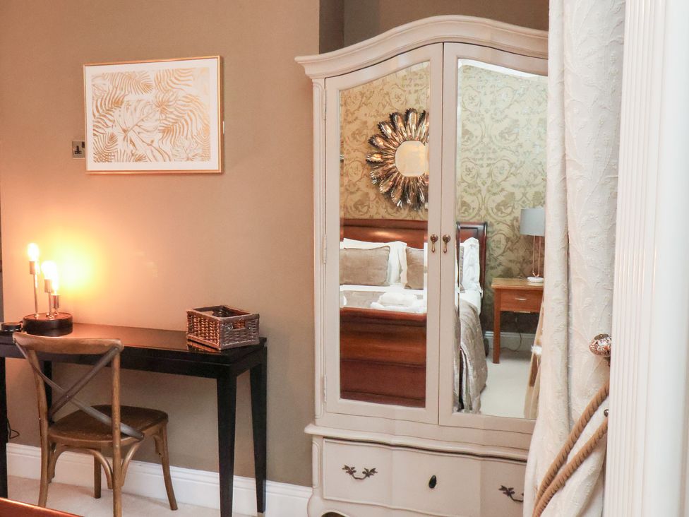 A bedroom with a wardrobe and a desk at All Seasons in Filey