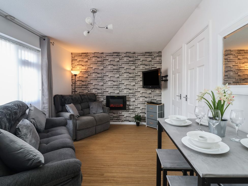 A living room with a sofa, television, and dining table at Flat 8 Burnham-on-Sea