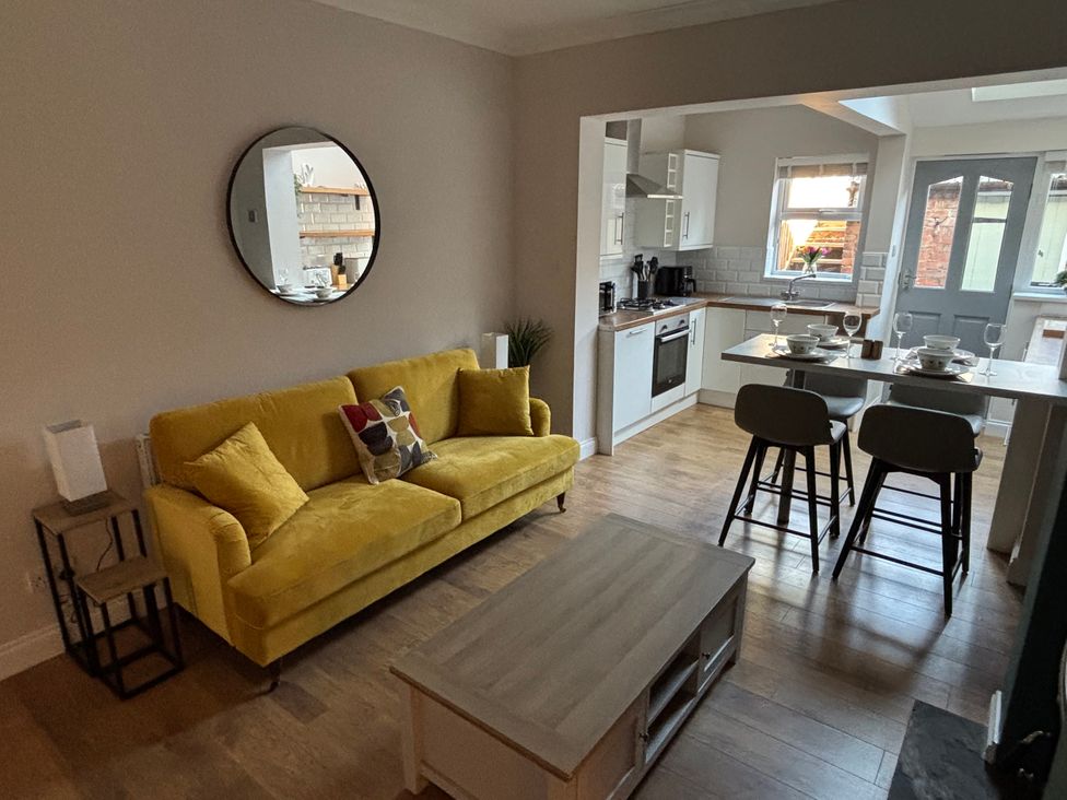 A living room with a yellow sofa and kitchen area at 97 Mayfield Road Ashbourne