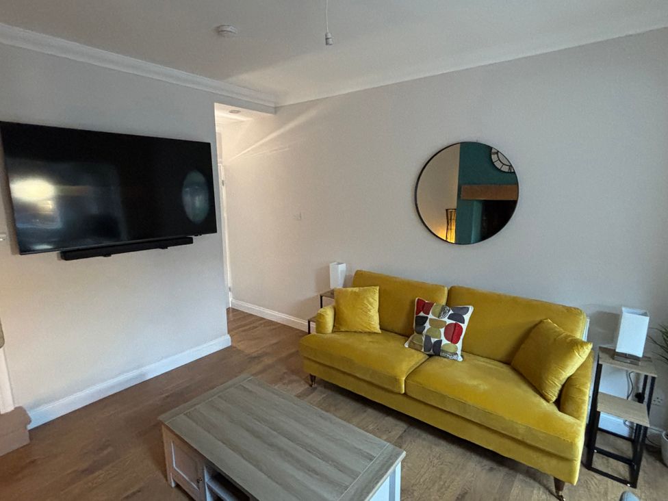 A living room with a yellow sofa and television at 97 Mayfield Road in Ashbourne