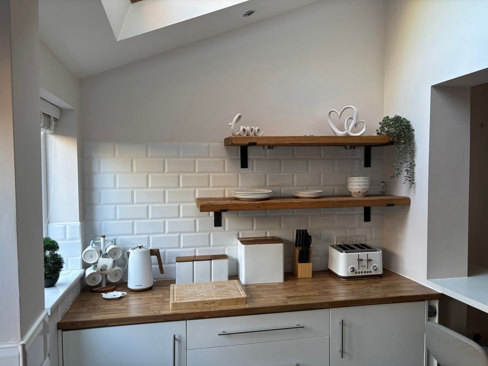 A kitchen with appliances and wooden shelves at 97 Mayfield Road in Ashbourne