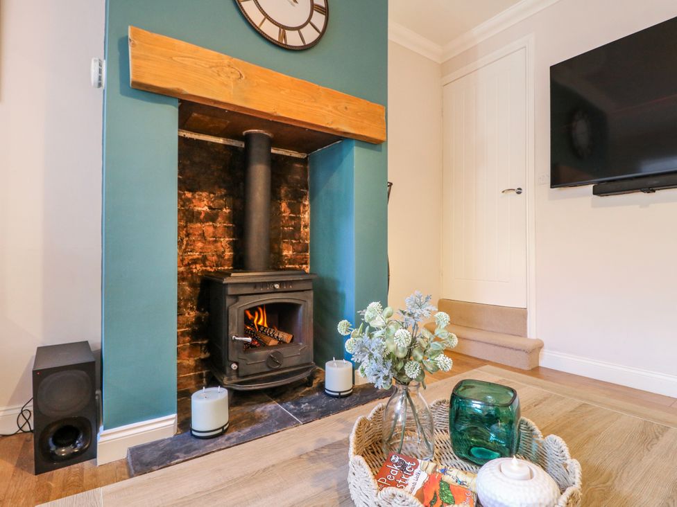 A living room with a fireplace and television at Hill View Cottage Ashbourne
