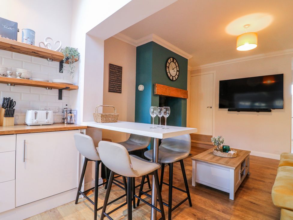 A kitchen with bar stools and a table at Hill View Cottage in Ashbourne