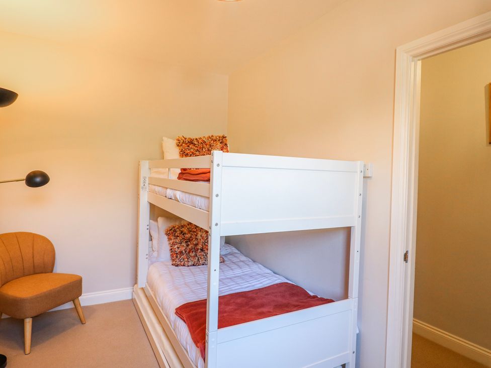 A bedroom with a bunk bed and an orange chair at Hill View Cottage in Ashbourne