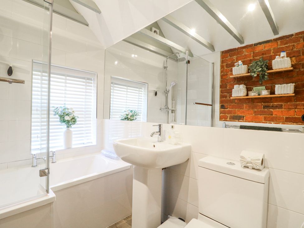 A bathroom with a shower, bathtub, and washbasin at Hill View Cottage, Ashbourne