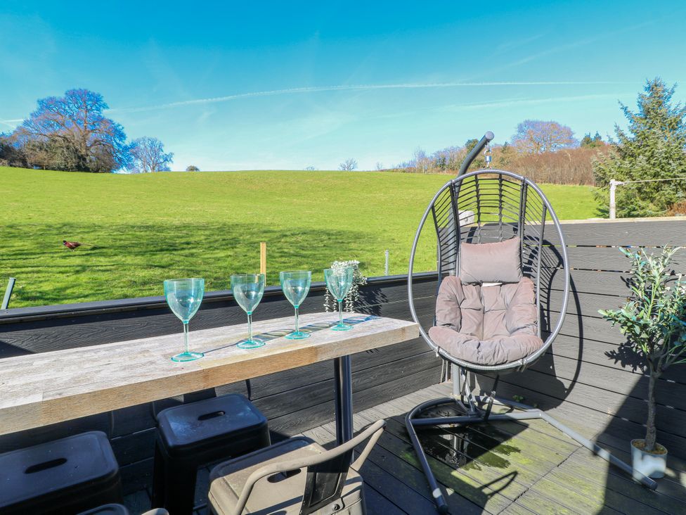 A table with glasses and a hanging chair at Hill View Cottage in Ashbourne