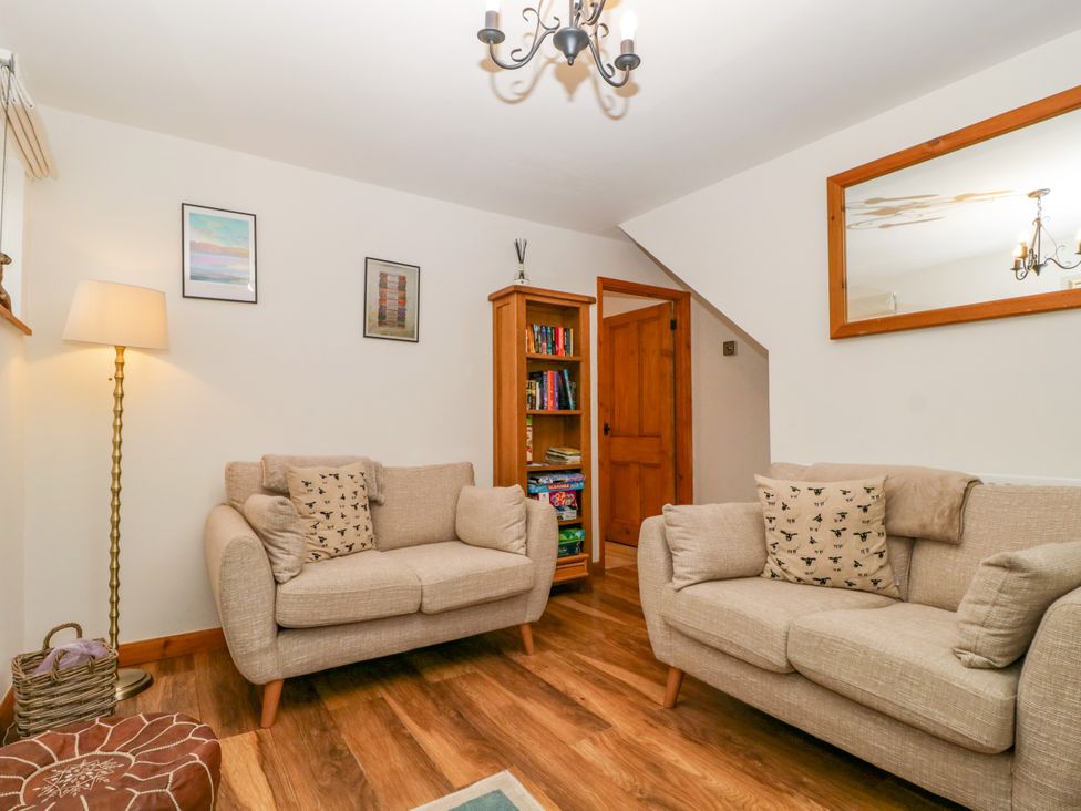 A living room with two sofas and a bookshelf at Capella Cottage in Keswick