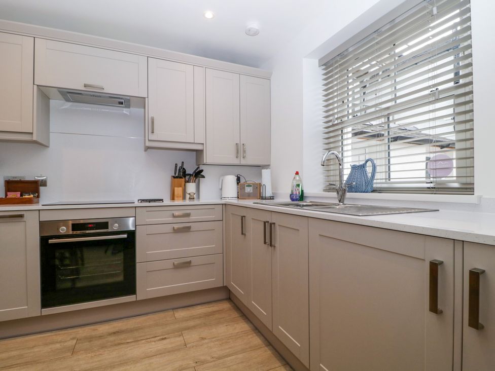 A kitchen with cabinets, oven, sink, and utensils at Capella Cottage in Keswick