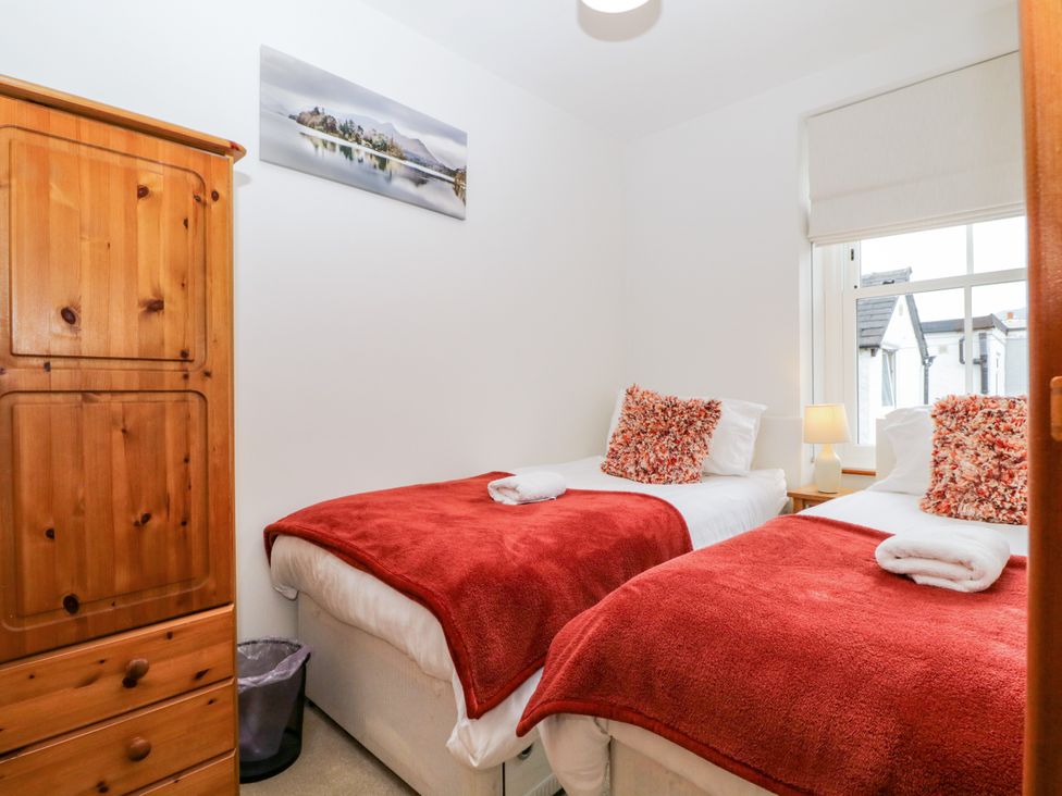 A bedroom with two beds and a wardrobe at Capella Cottage in Keswick