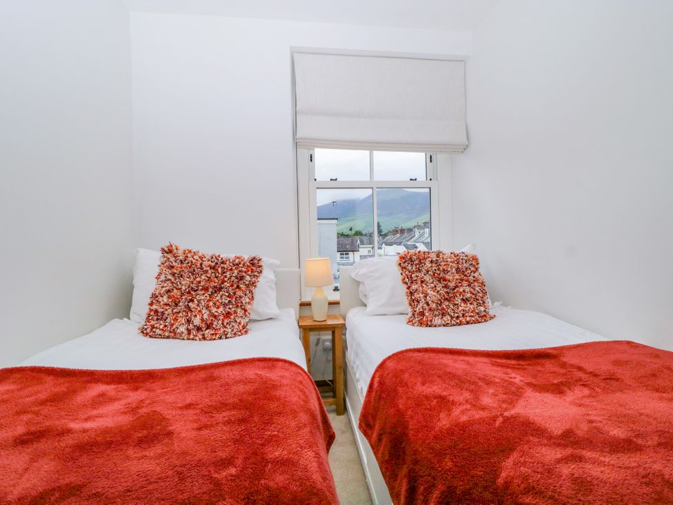 A bedroom with two beds and a lamp at Capella Cottage in Keswick