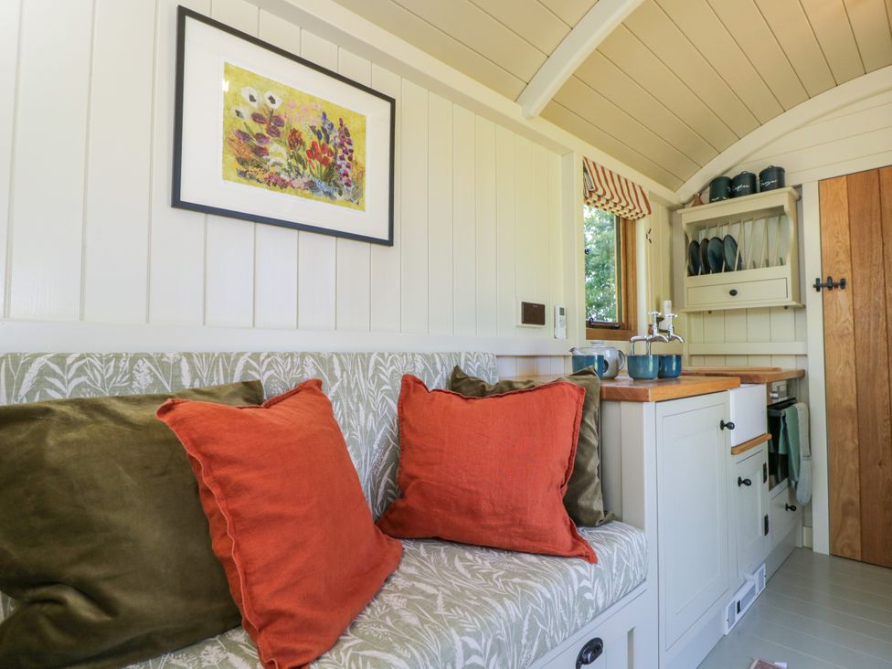 A kitchen area with a patterned bench seat and cushions an oven and wooden countertop at Blackthorn South Leigh near Witney
