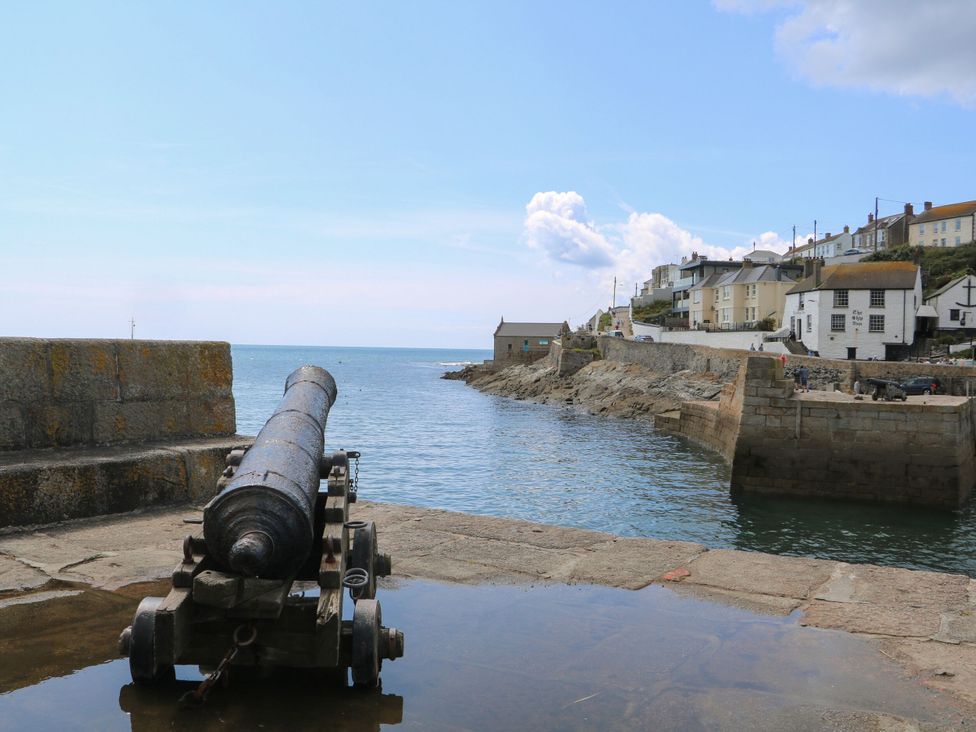 A cannon by the water with houses in the background at The Loft in Porthleven