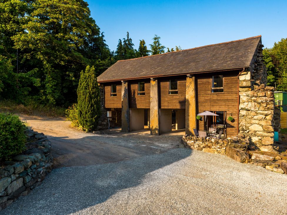 A building surrounded by trees with a gravel driveway at Idris Barn in Dolgellau
