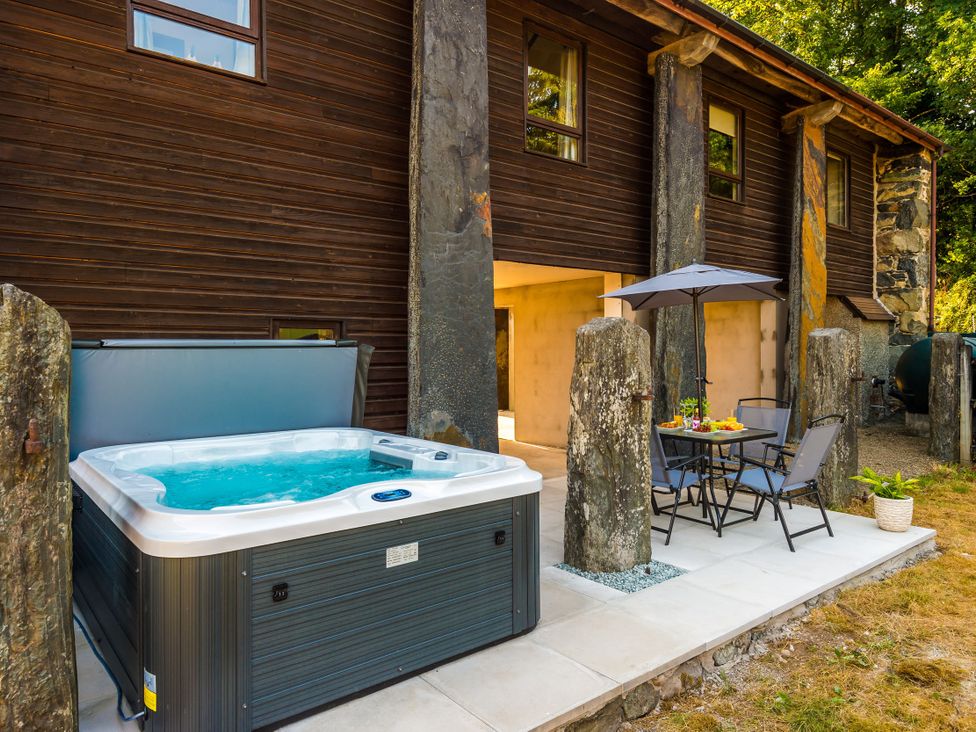 An outdoor area with a hot tub and seating at Idris Barn Dolgellau