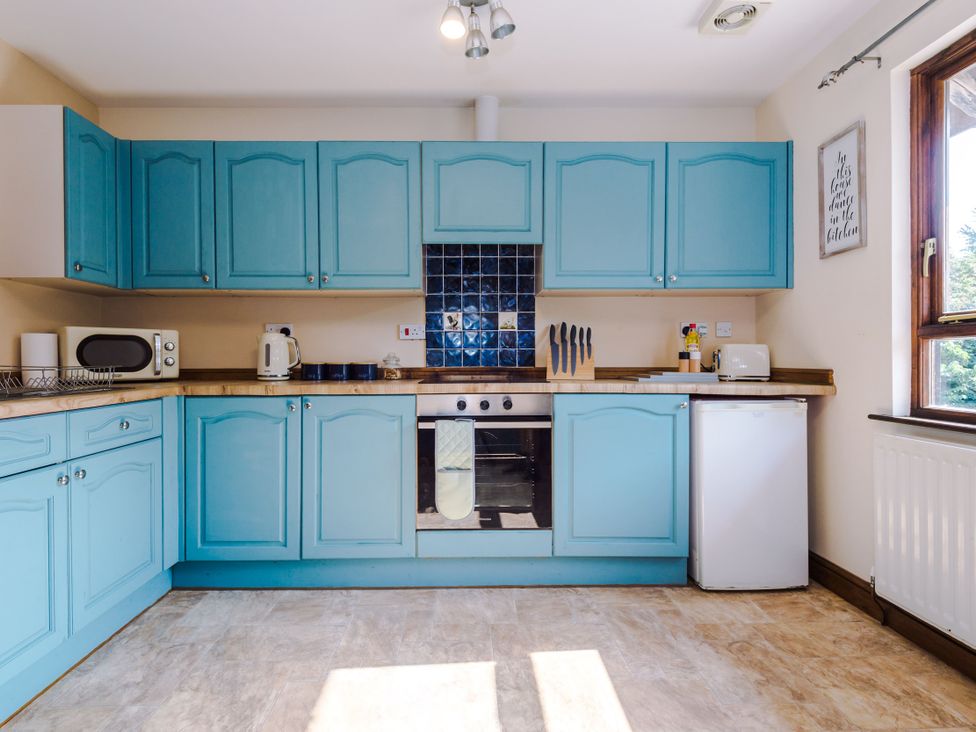 A kitchen with blue cabinets and appliances at Idris Barn Dolgellau
