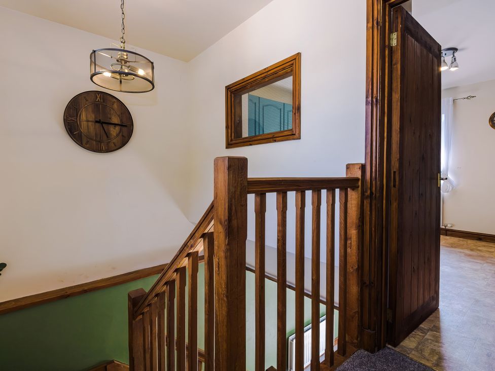 A hallway with a staircase and clock at Idris Barn Dolgellau