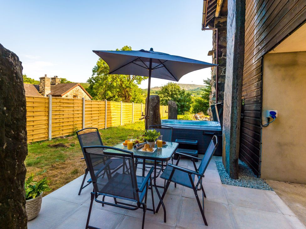 An outdoor area with a table and chairs under an umbrella at Idris Barn Dolgellau