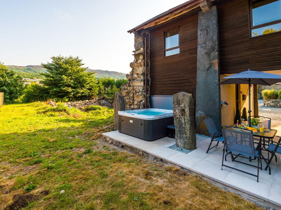 A garden with a hot tub, table, and chairs at Idris Barn Dolgellau