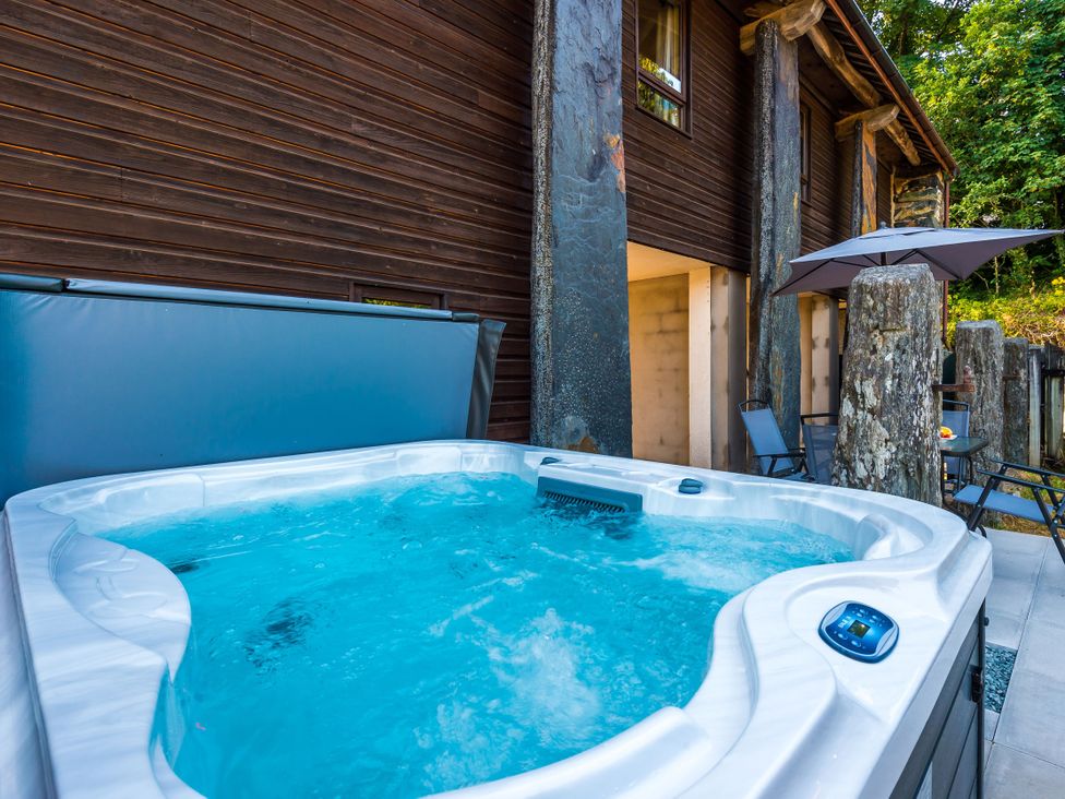 A hot tub with water beside wooden wall and stone pillars at Idris Barn Dolgellau