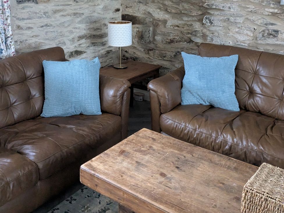 A living room with sofas and a wooden table at La Bastille in Maenclochog