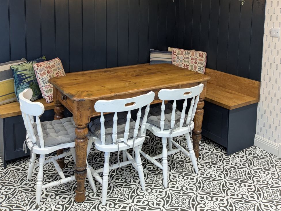 A dining room with a wooden table and white chairs at La Bastille in Maenclochog