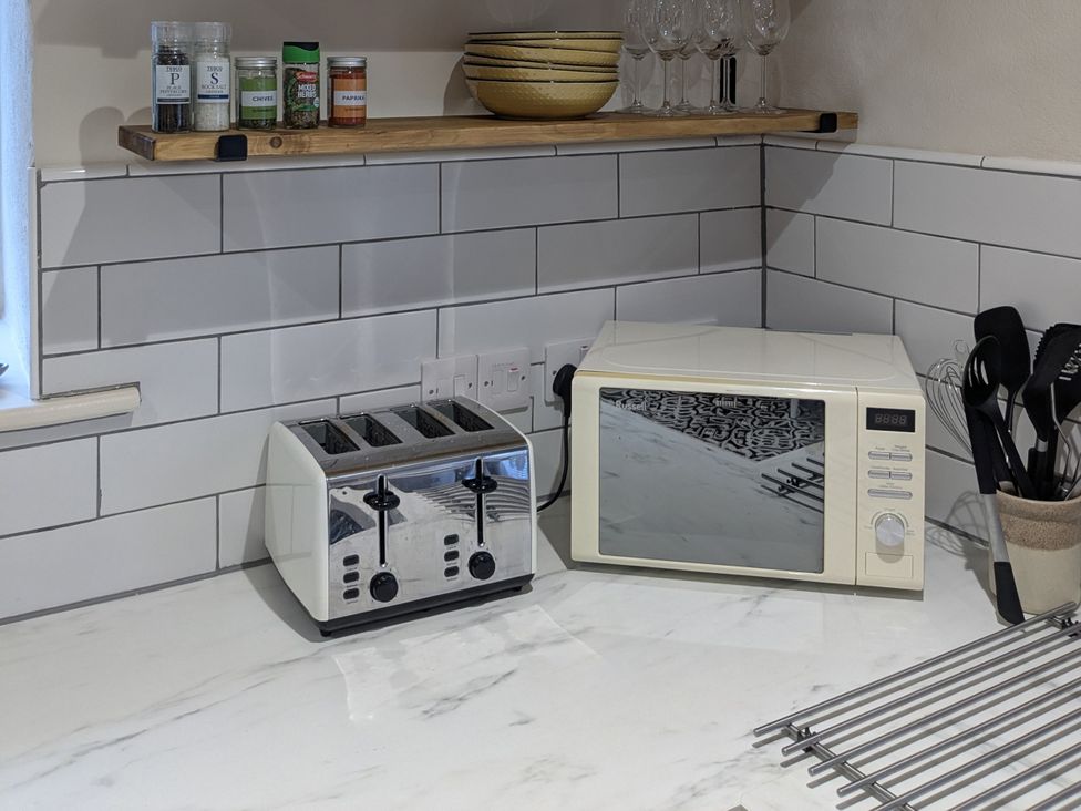 A kitchen with a toaster and microwave on the counter at La Bastille in Maenclochog