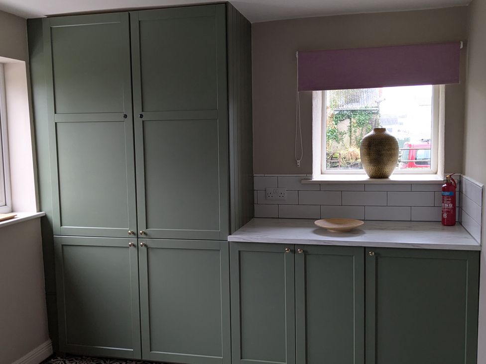 A kitchen with green cabinets and a window at La Bastille in Maenclochog