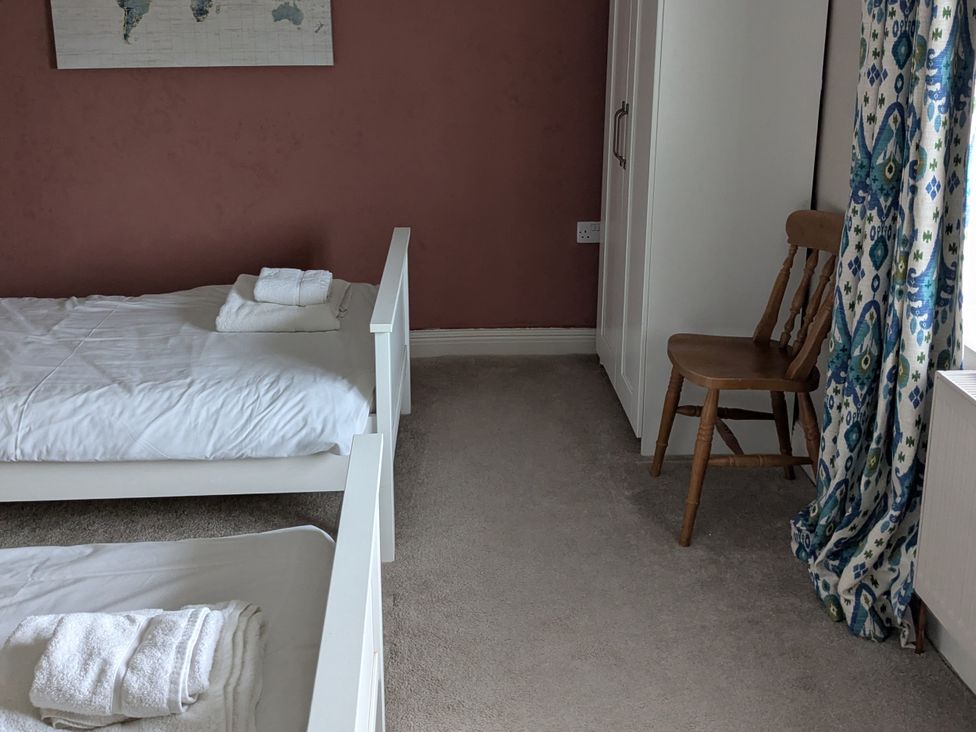A bedroom with two beds and a chair at La Bastille in Maenclochog