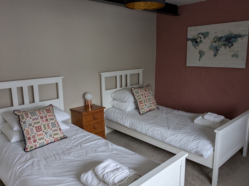 A bedroom with two single beds and a bedside table at La Bastille in Maenclochog