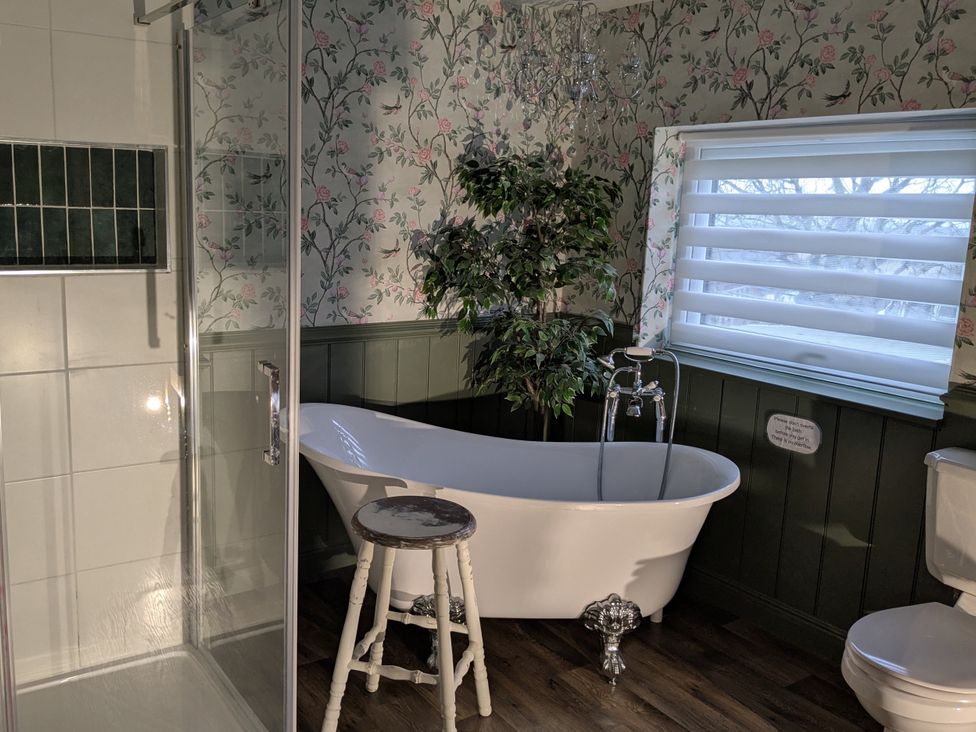 A bathroom featuring a bathtub, shower, toilet, and a plant at La Bastille Maenclochog