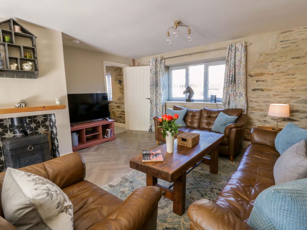 A living room with a television and leather sofas at La Bastille in Maenclochog