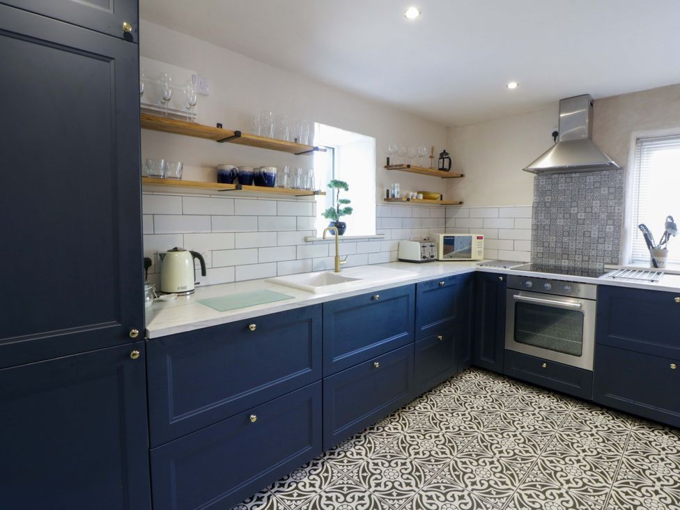 A kitchen with blue cabinets and appliances at La Bastille in Maenclochog