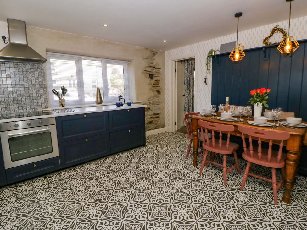 A kitchen with cabinets, a dining table and chairs at La Bastille in Maenclochog